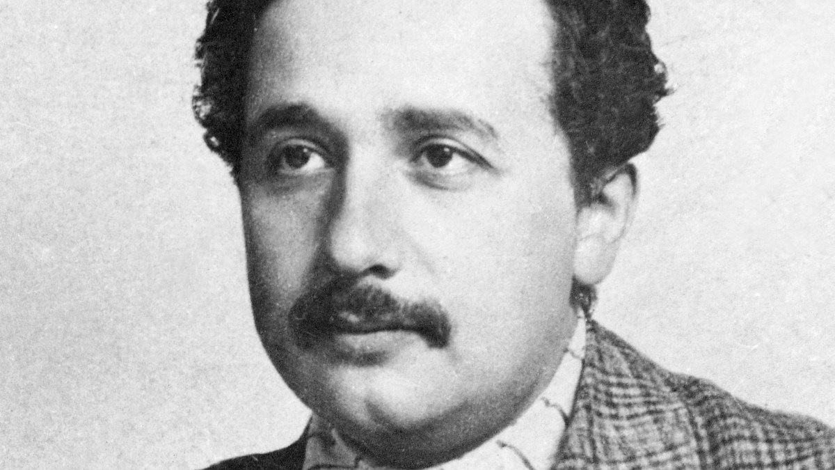 A black and white photo of a man with a mustache.