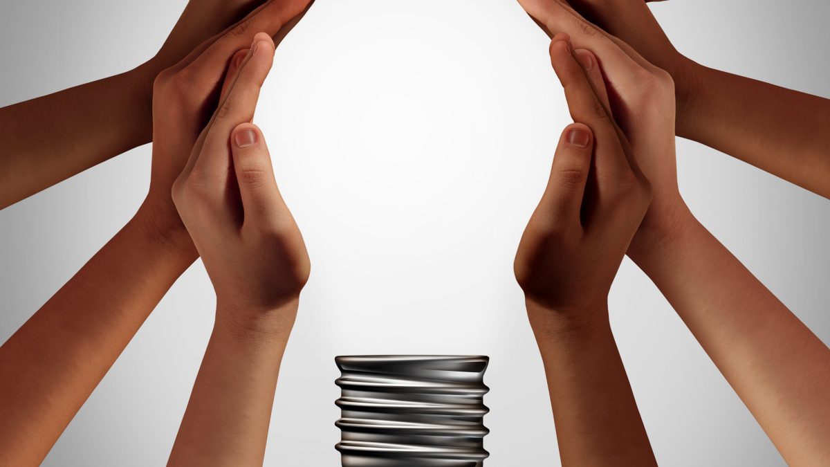 Hands coming together to form the shape of a light bulb.