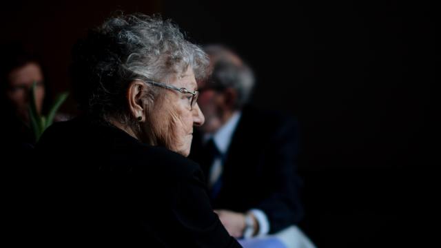 an older woman against a dark background illustrating aging loneliness and regret