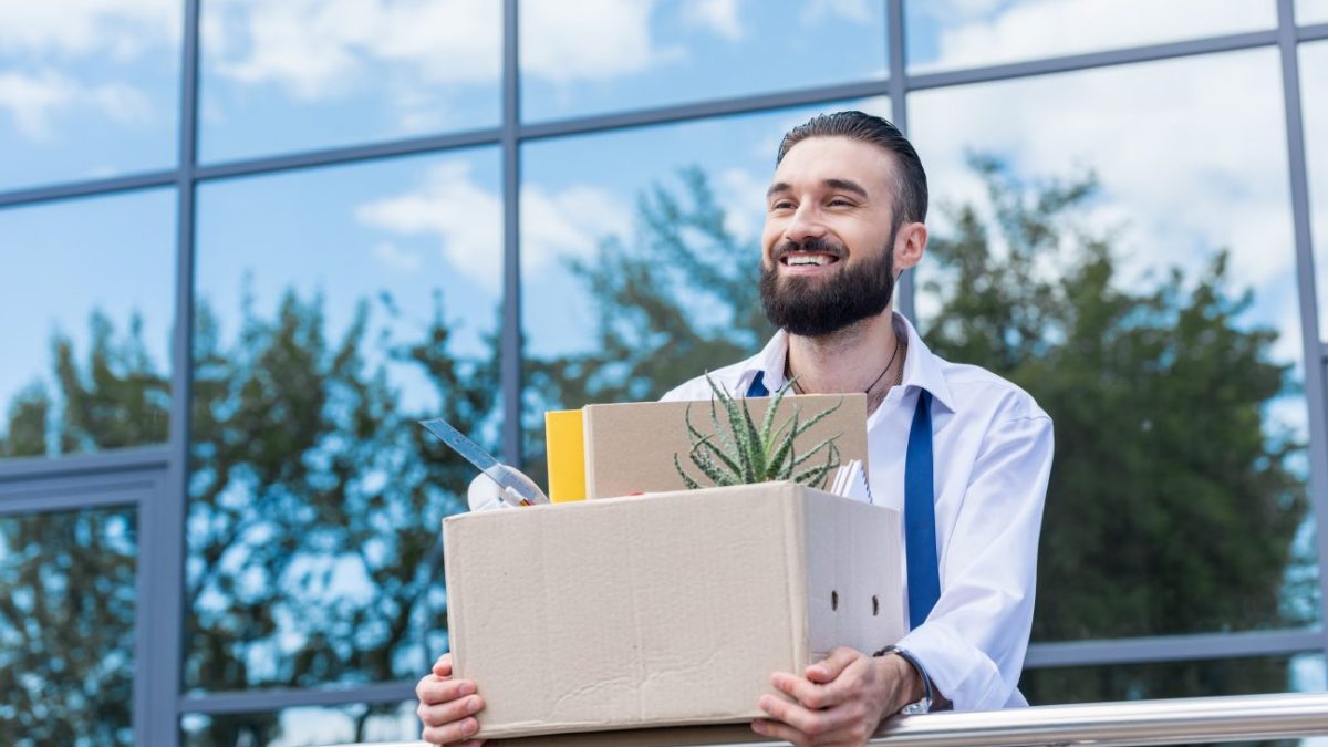 A businessman quits his job as part of the Great Resignation and smiles contently.
