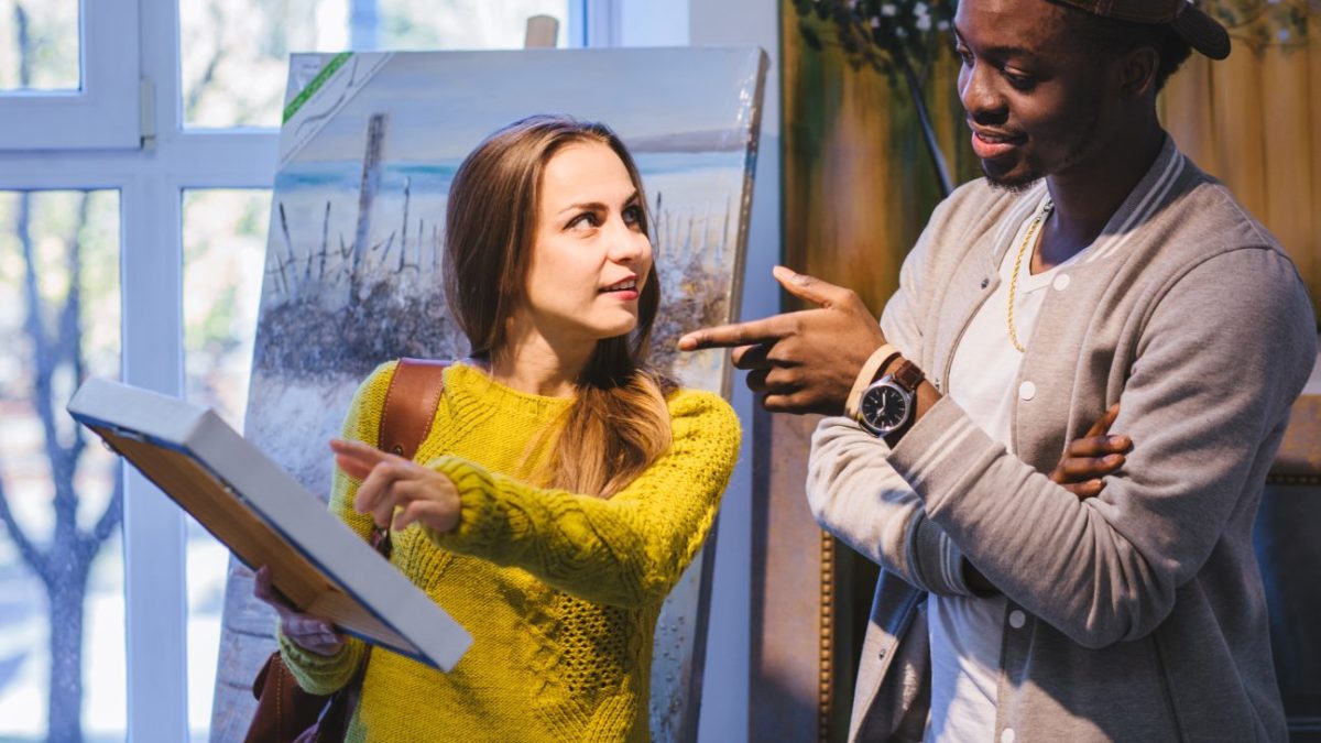 A young couple discuss a painting.