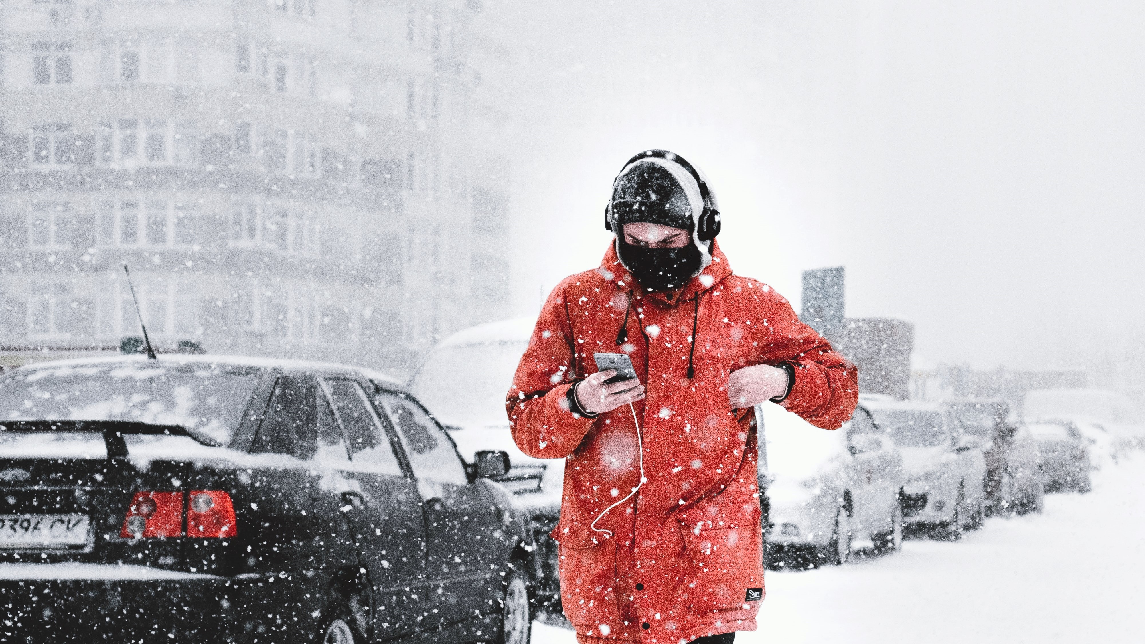 A man walks through the snow listening to music on his headphones.