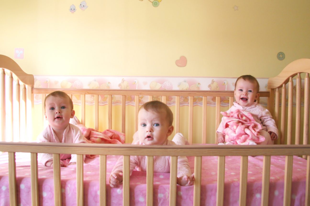 Baby girl triplets in a crib together.