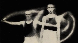 Two men in athletic clothing stand against a black background, with glowing light trails swirling around them—symbolizing the energy and persistence involved in forming habits through dedication and motion.