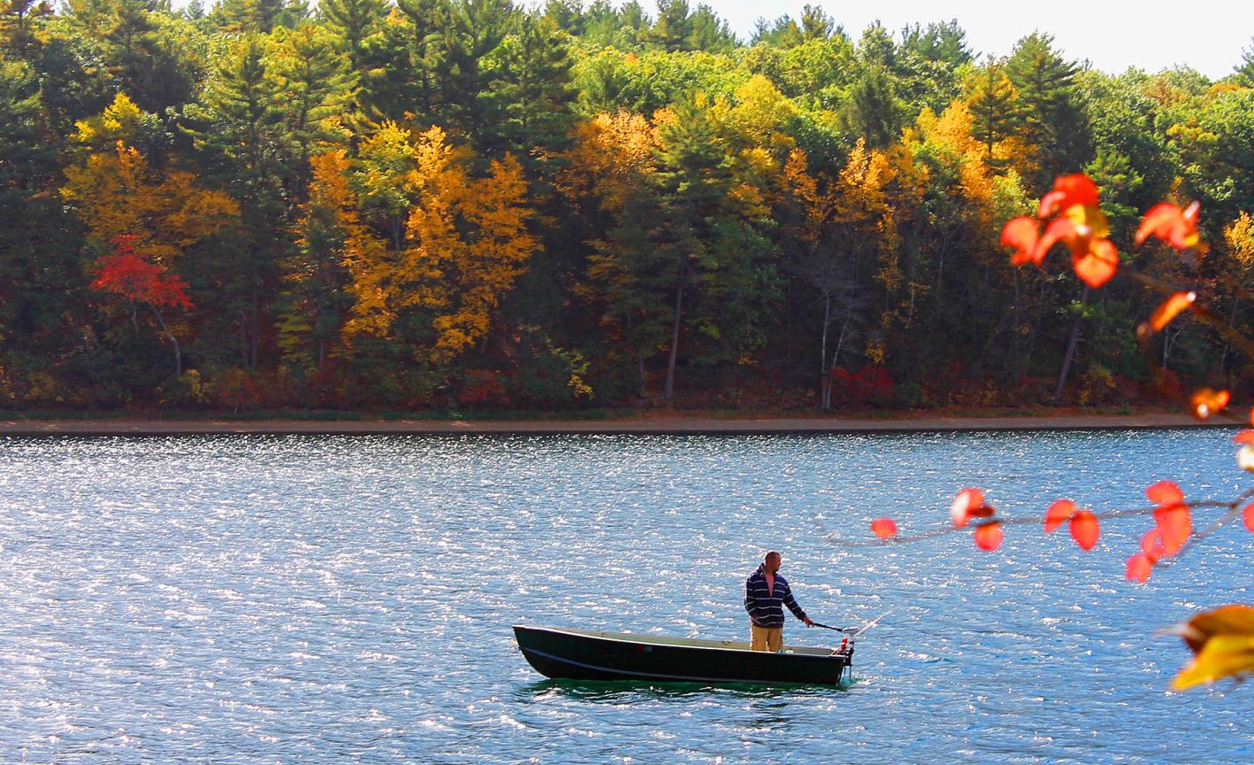 A man boats on Walden Pond in the fall.