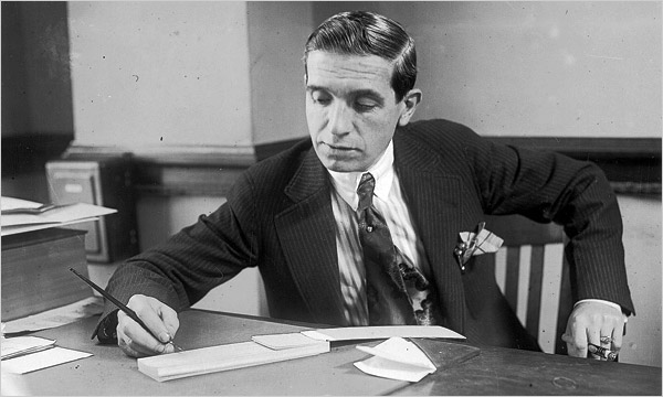Charles Ponzi writing at check at his desk.