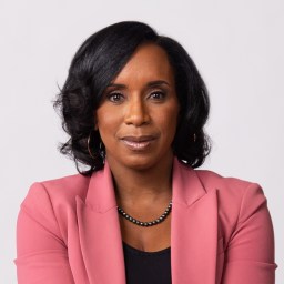 A black woman in a pink blazer.