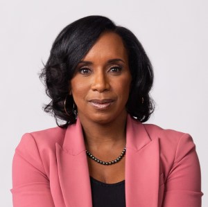 A black woman in a pink blazer.