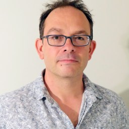 a man wearing glasses and a blue shirt.