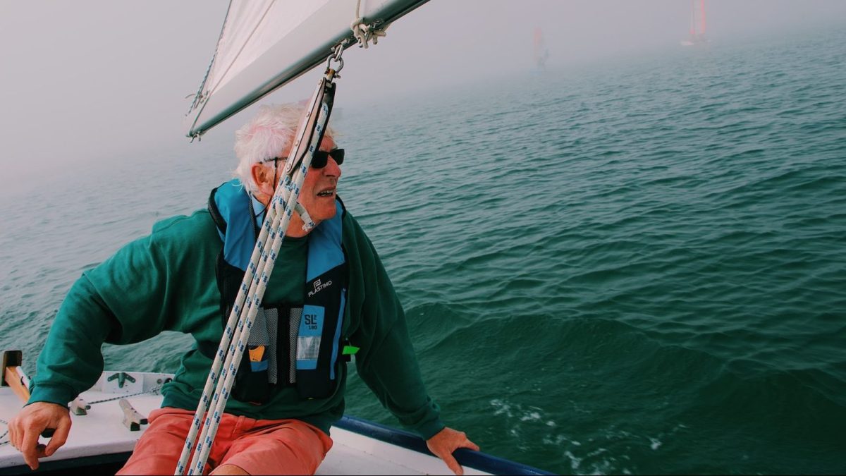 a man sitting on the bow of a sailboat.