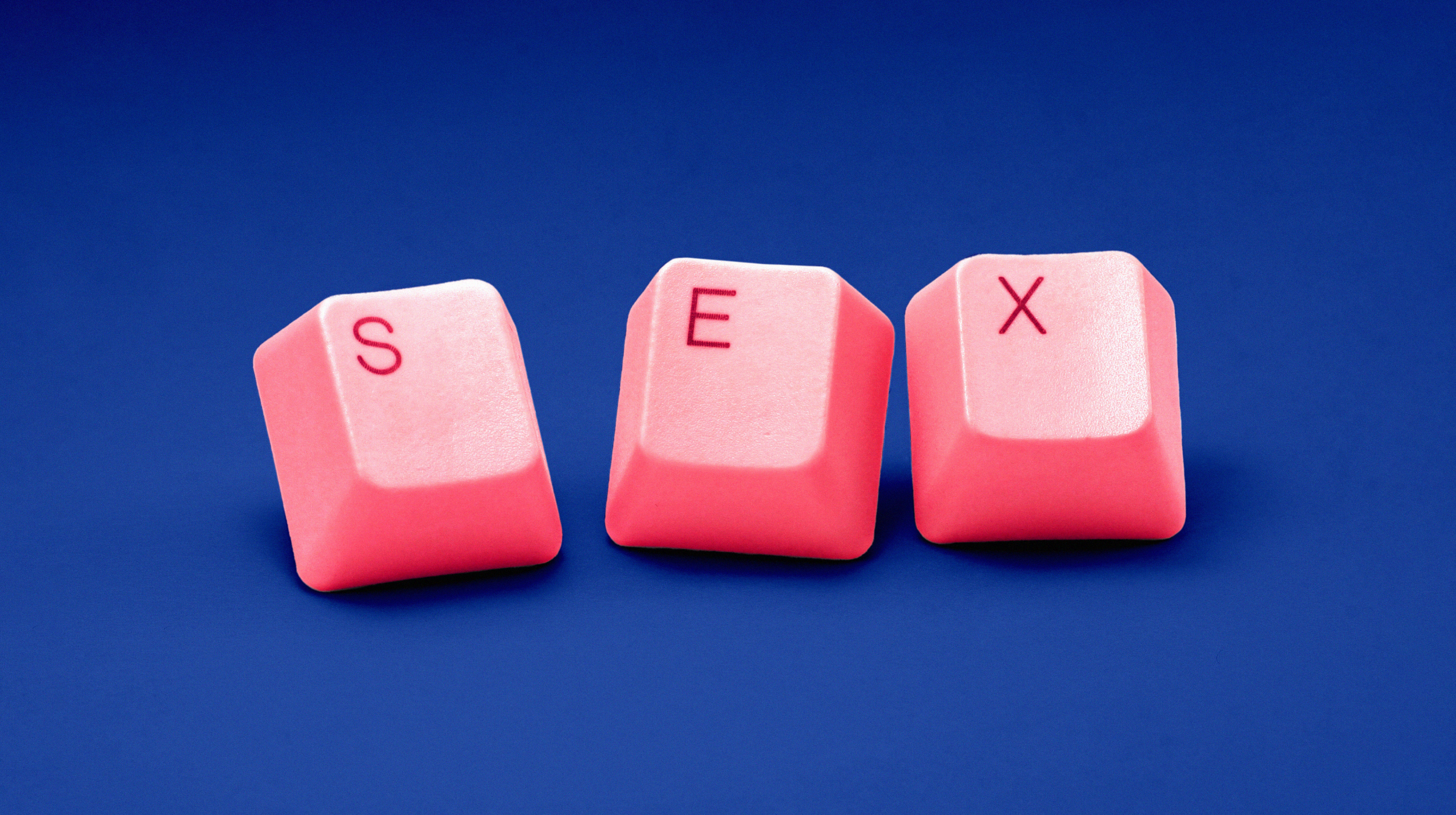 a pink computer keyboard with the word sex spelled on it.