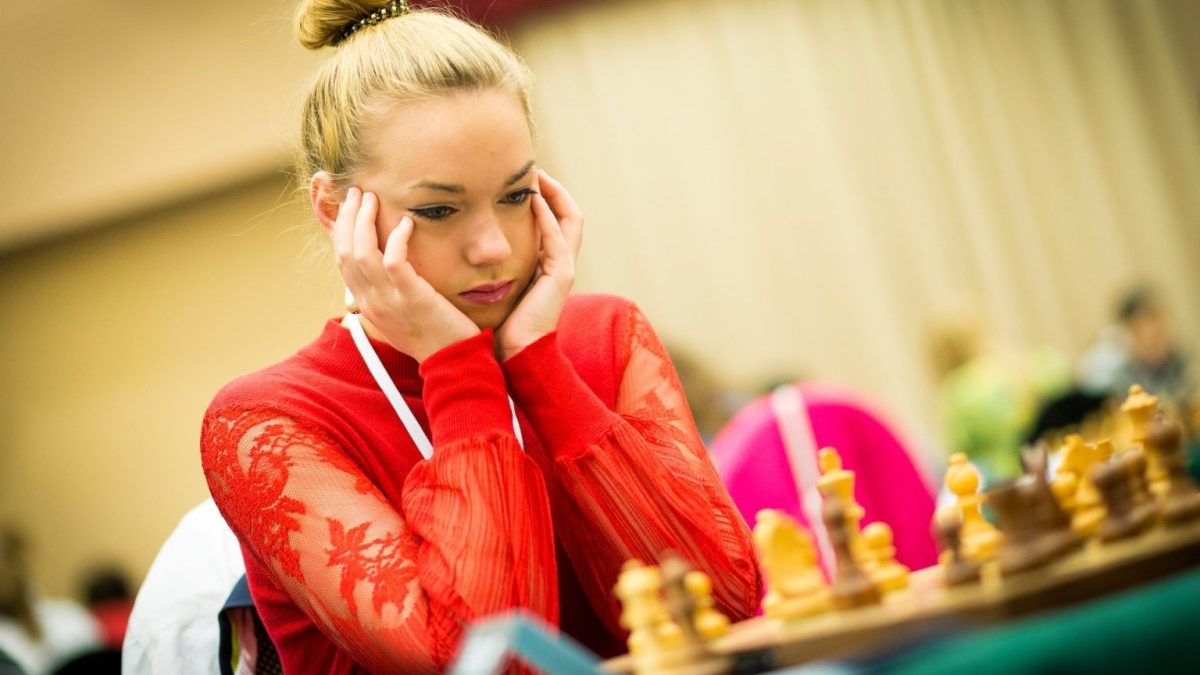 a woman sitting at a table with a chess board.