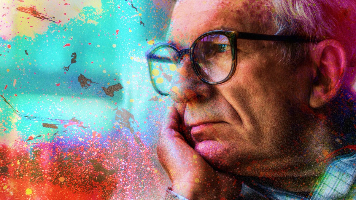 a man with glasses is looking out a window.