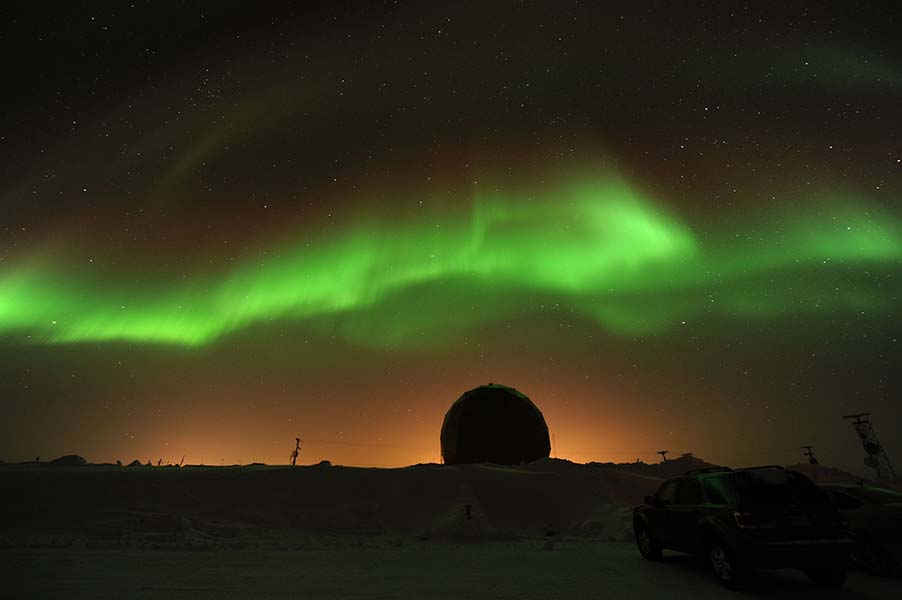 a green and yellow aurora bore is in the sky.