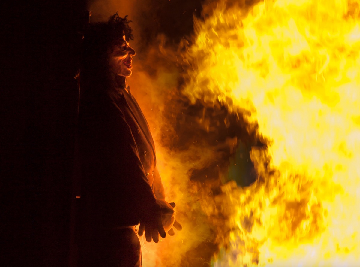 a man standing in front of a large fire.