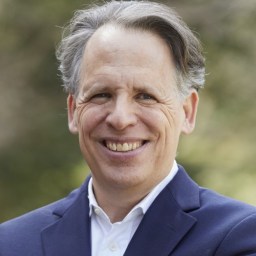 a close up of a person wearing a suit and smiling.