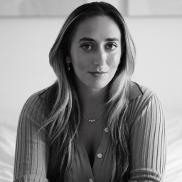 a black and white photo of a woman sitting on a bed.