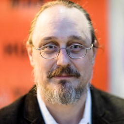 a man with glasses and a beard wearing a suit.