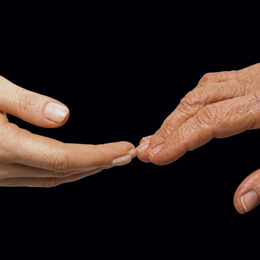 two hands reaching for each other on a black background.