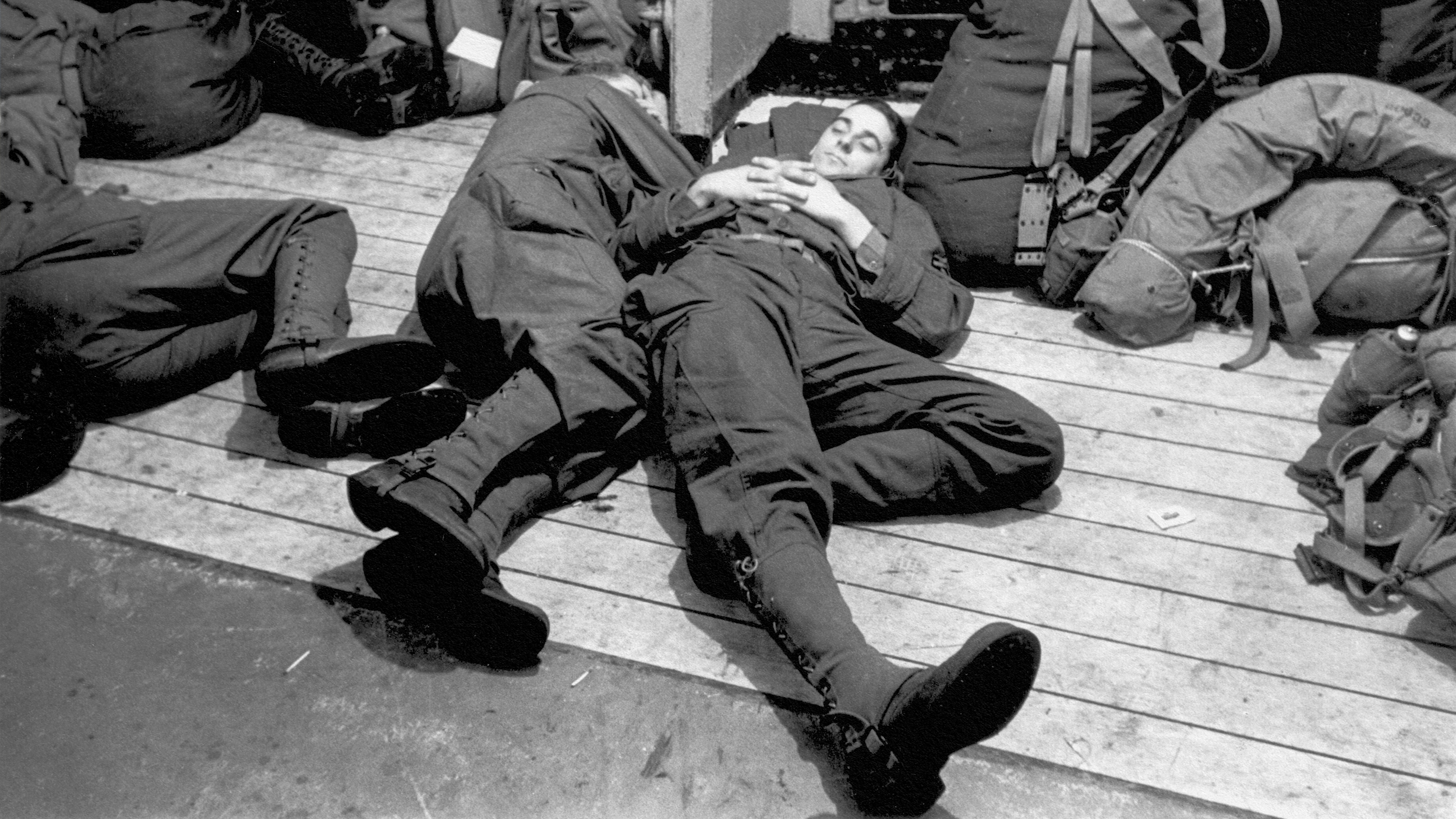 a black and white photo of two men laying on a dock.