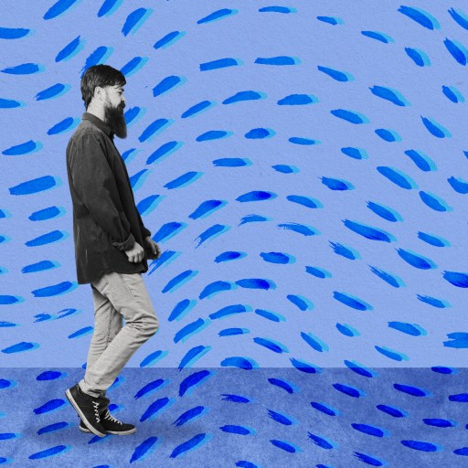 a man walking in front of a blue background.