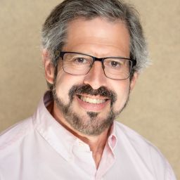 A man wearing glasses and a pink shirt.