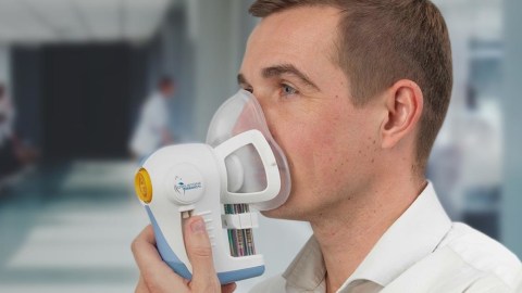 A man with liver disease is using a nebulizer in a hospital.