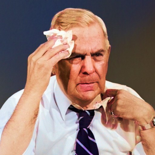 A man in a tie is holding a tissue to his face.