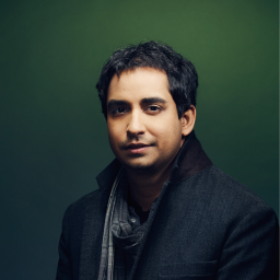 A man standing in front of a green background.