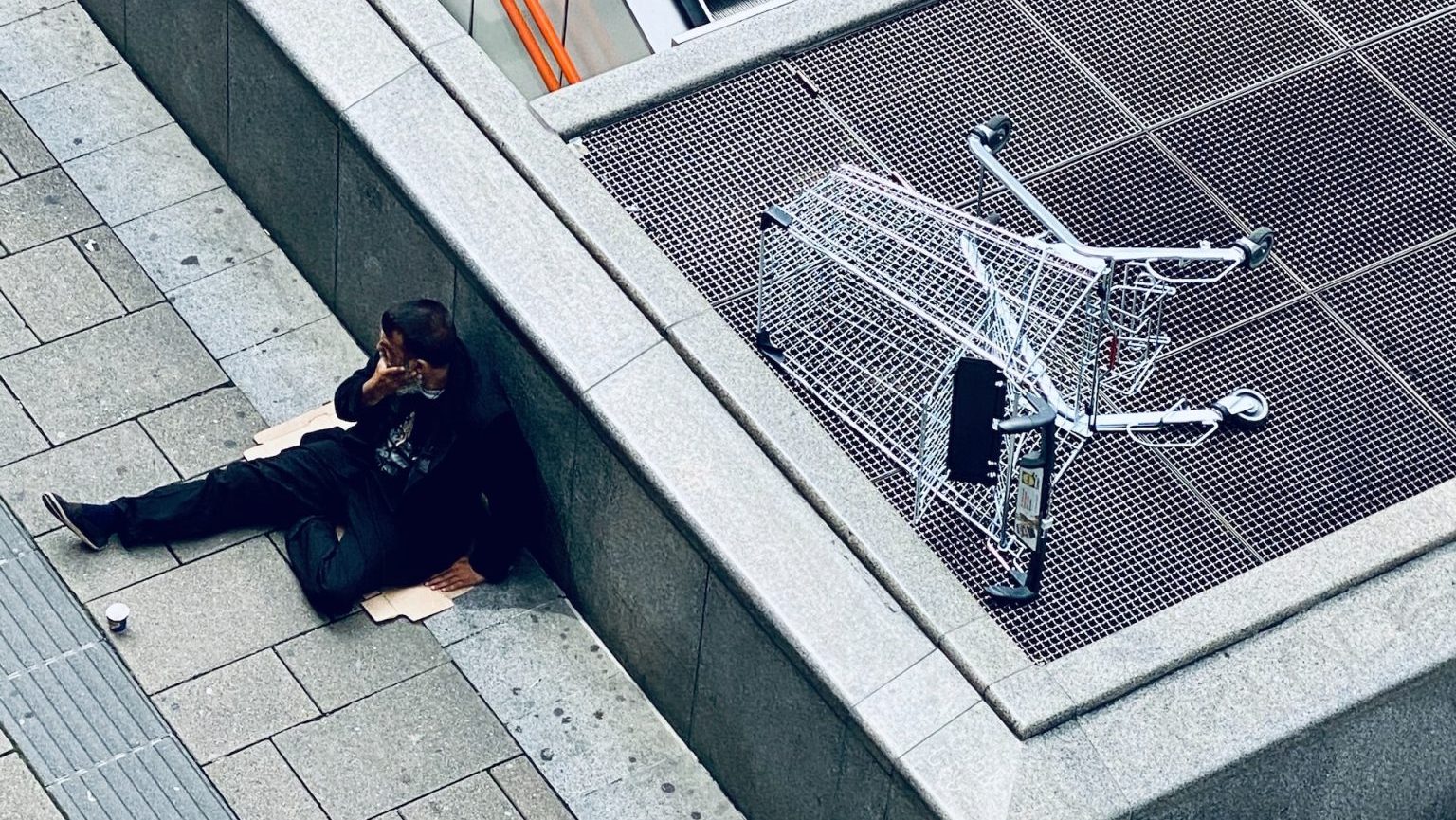 A man is laying on the ground next to an escalator.
