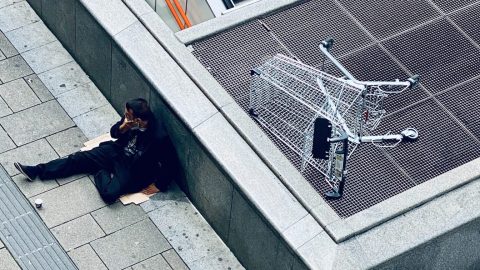 A man is laying on the ground next to an escalator.