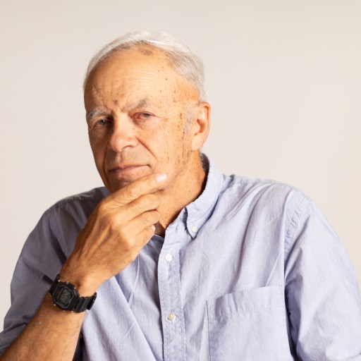 An older man pondering with his hand on his chin, contemplating effective altruism.