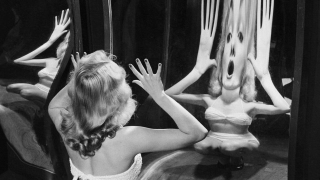 A woman is looking at herself in a mirror.