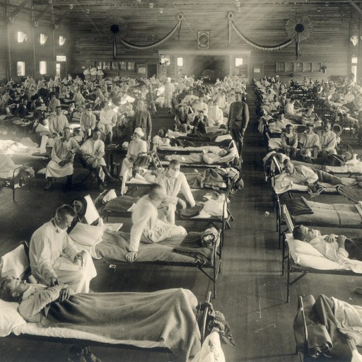 During the 1918 flu pandemic, a group of individuals lay together on beds in a vast room, seeking solace and care.