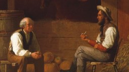 Two men sit facing each other in a barn with pumpkins behind them; one man holds a pipe, and both appear to be engaged in conversation.