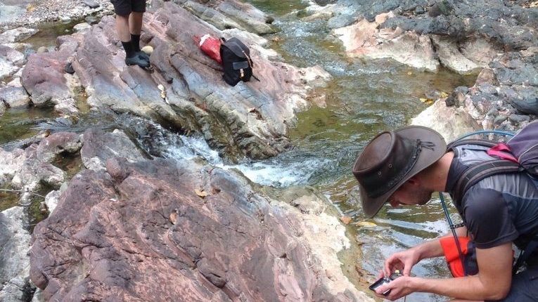A group of hikers standing on rocks near a stream.