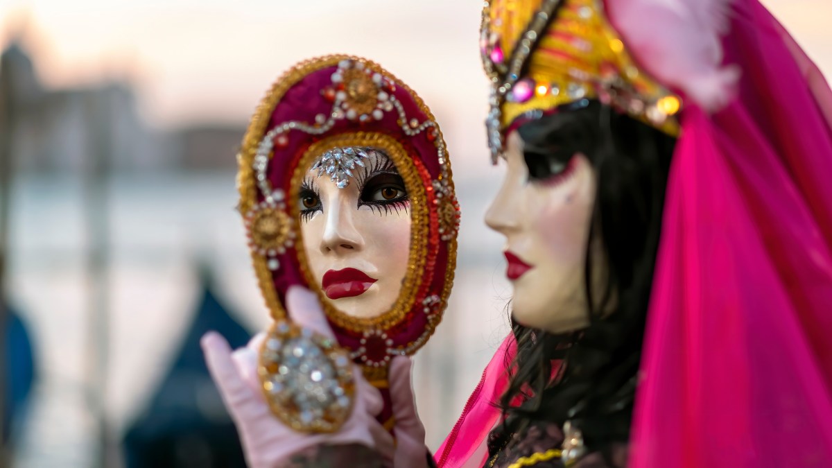 A woman in a pink mask is holding a Nietzsche mirror.