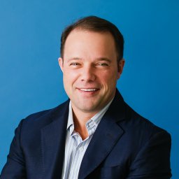 A man in a blue shirt is smiling.