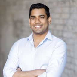 A man with his arms crossed in front of a brick wall.