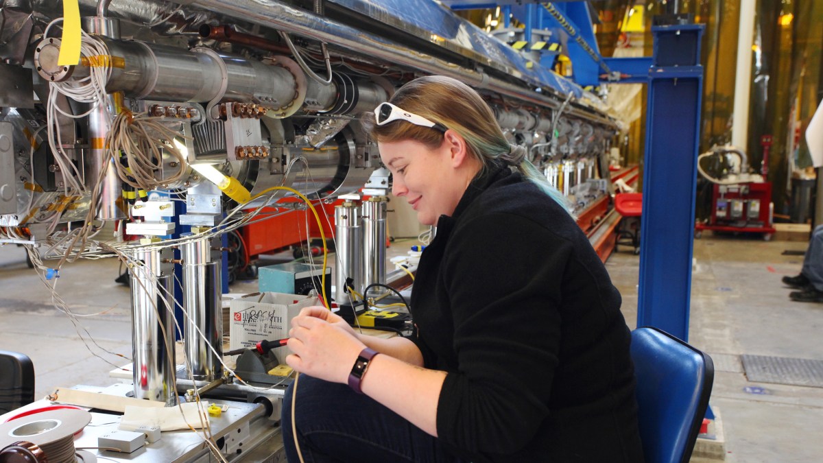 A woman operating an x-ray laser machine in a factory.