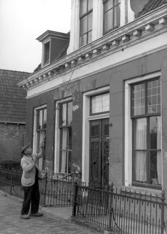 An old black and white photo of a man cleaning a house.