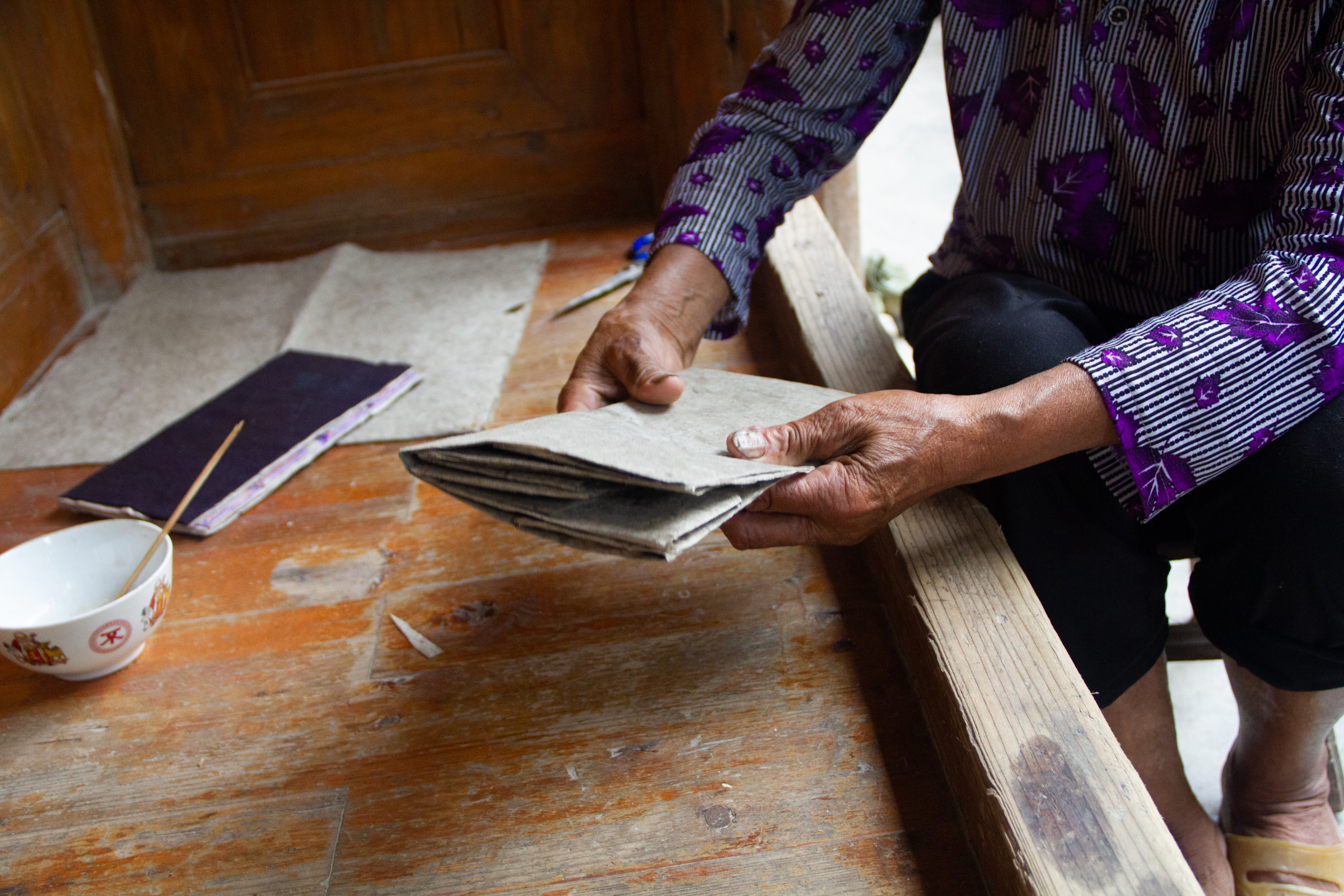 A woman is sitting on a wooden bench under a bright moon.