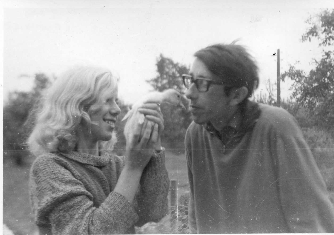 An old black and white photo of a man and woman holding a bird.