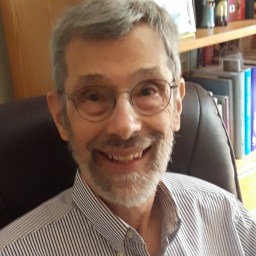 A man with glasses and a beard sitting in a chair.