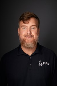 A man with a beard wearing a black polo shirt.