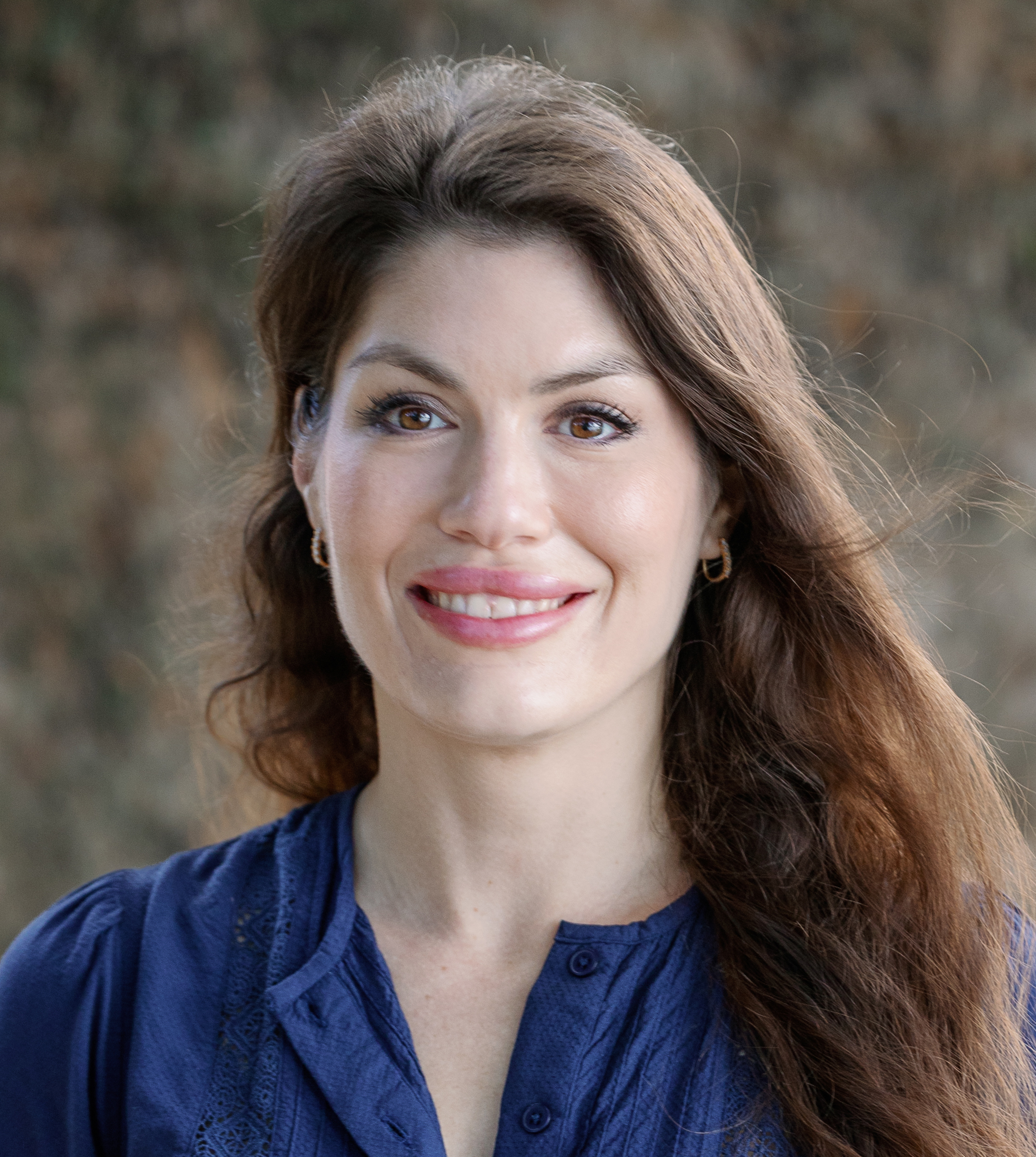 A woman in a blue shirt smiles for the camera.