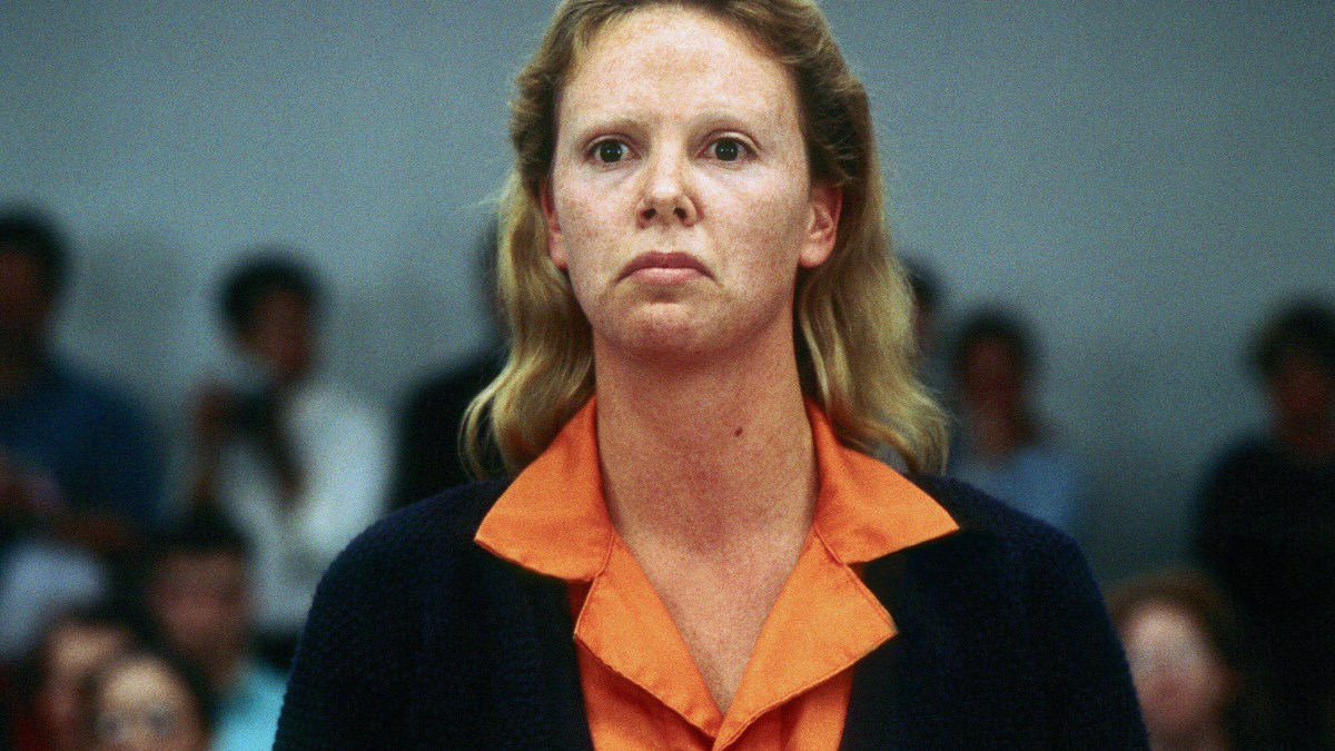A woman in an orange shirt standing in front of a crowd.