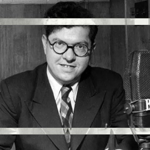 Man in a suit posing with a vintage BBC Big Bang 75 microphone.