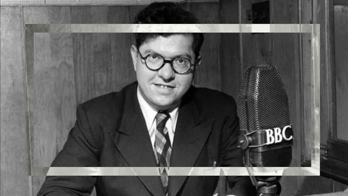 Man in a suit posing with a vintage BBC Big Bang 75 microphone.