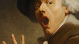 A person with white hair and a dark hat looks surprised, mouth open and eyes wide, holding up one hand with fingers spread.